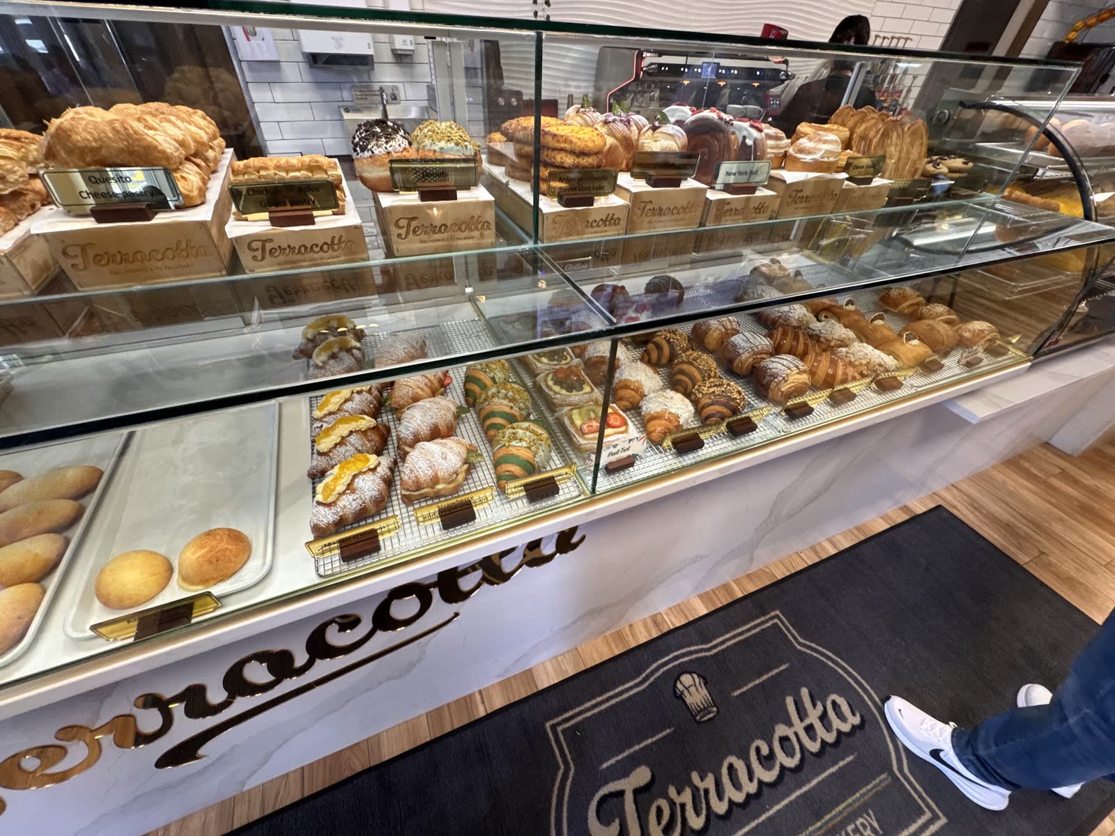 Glass pastry case packed with croissants, rolls, tarts, and donuts