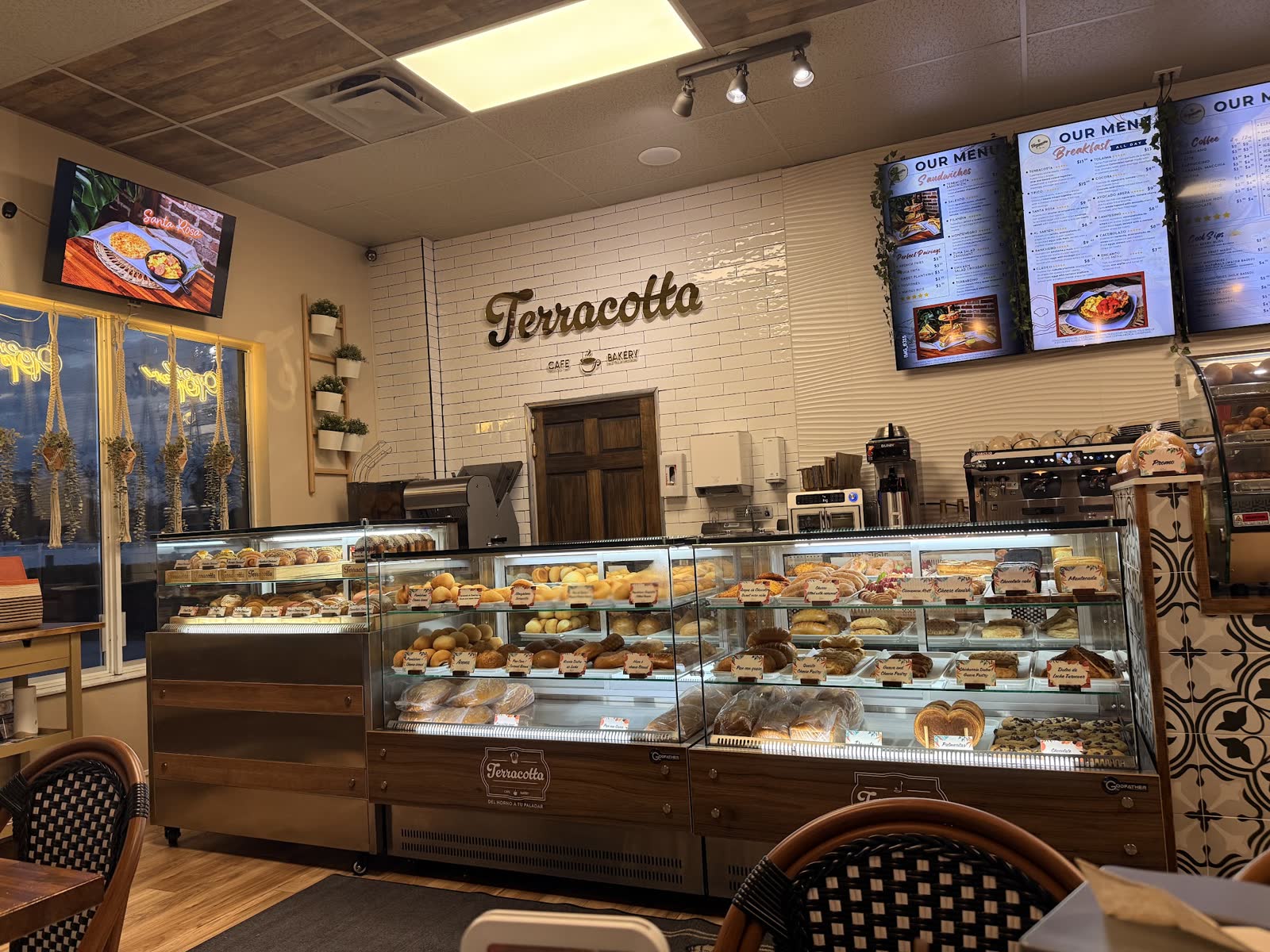 Service counter, three pastry cases, wall sign, and seating at Terracotta Cafe & Bakery