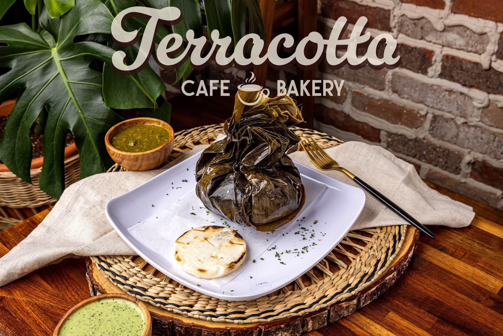 A plated breakfast with a leaf-wrapped item, arepa, and two sauces