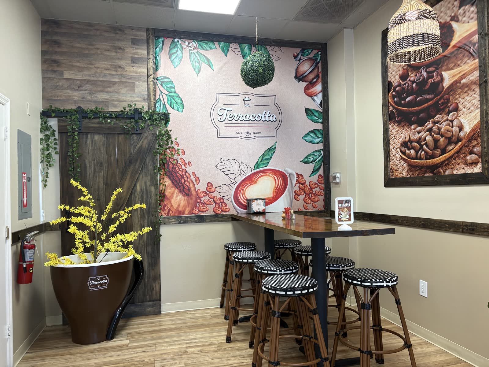 High-top seating in front of a Terracotta Cafe & Bakery coffee mural